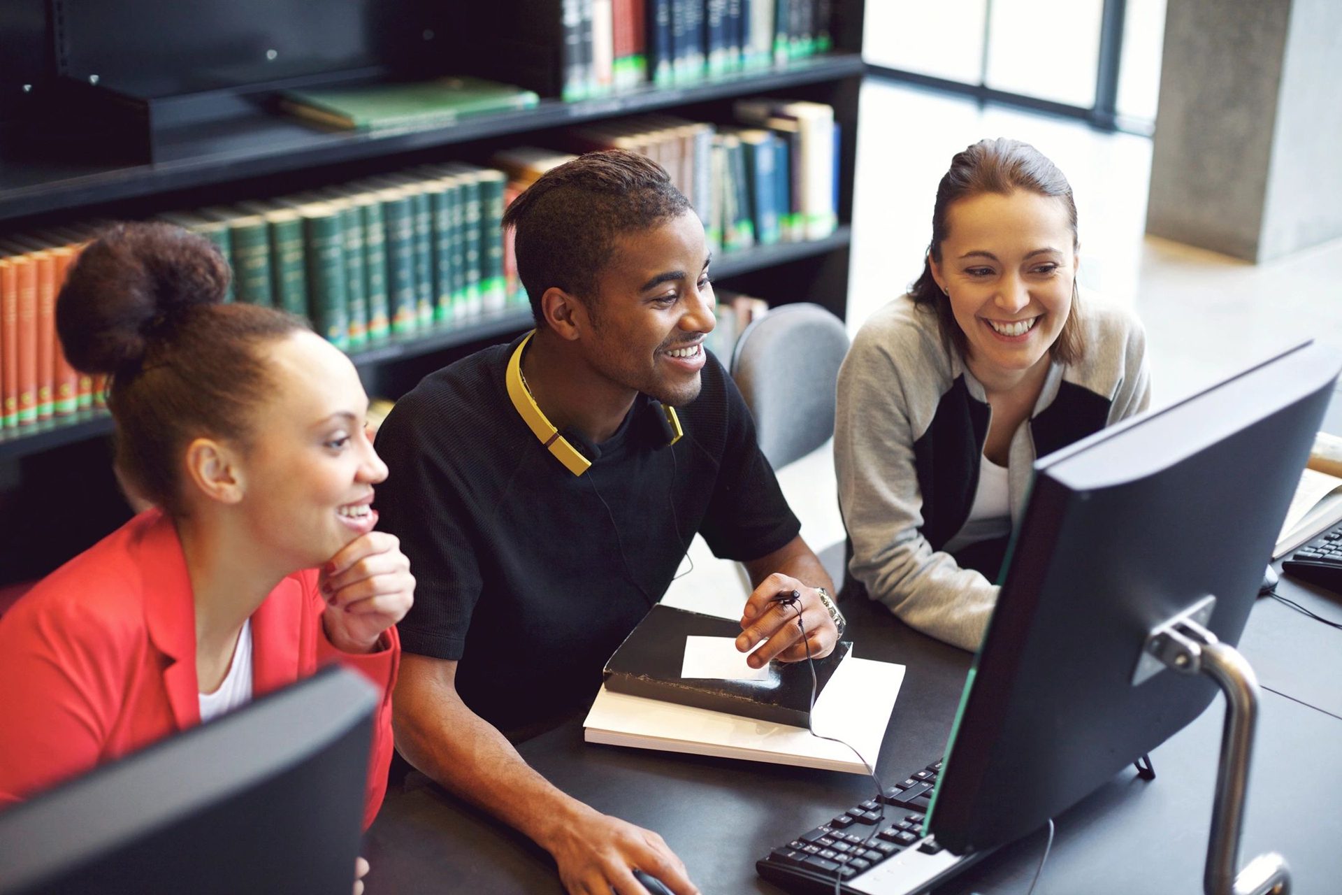 Students collaborating in a library on computers.