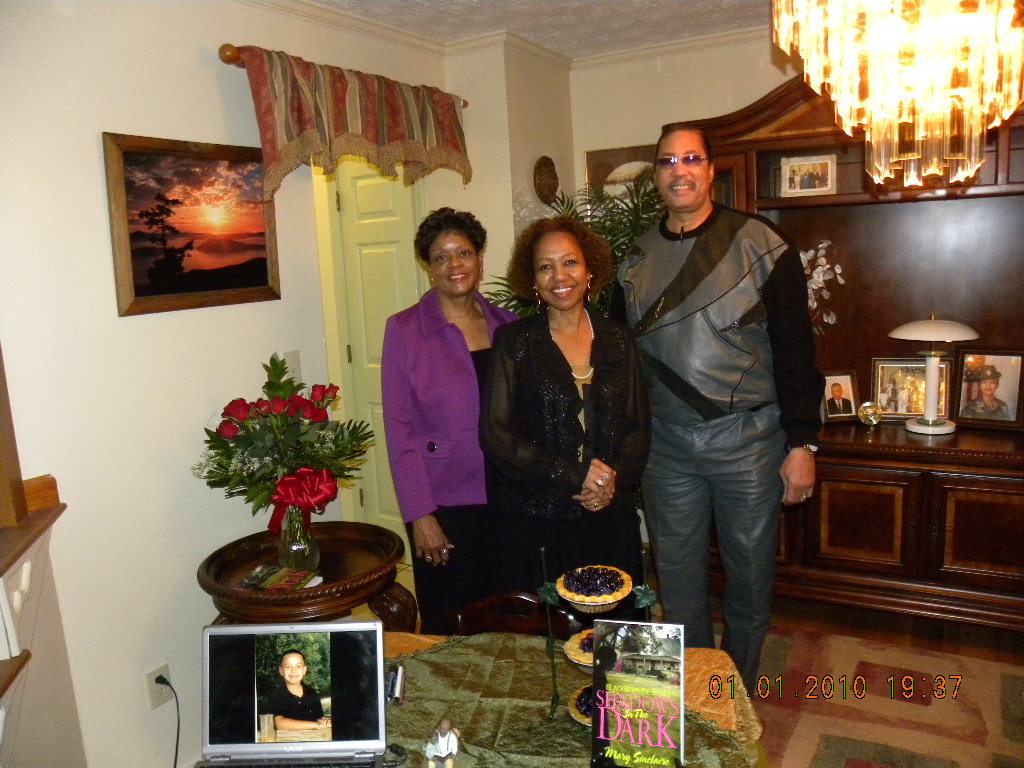 Three people smiling in a warmly decorated living room.